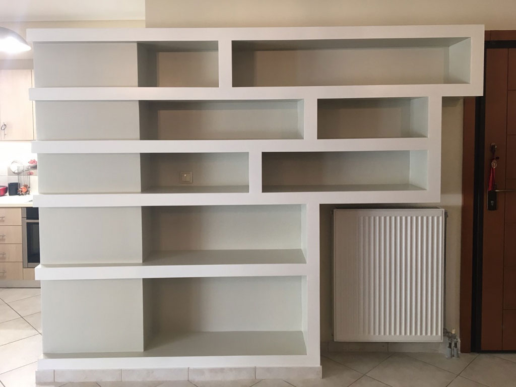 Διαχωριστική βιβλιοθήκη από γυψοσανίδα με γεωμετρικά ράφια σε κατοικία στη Μεταμόρφωση