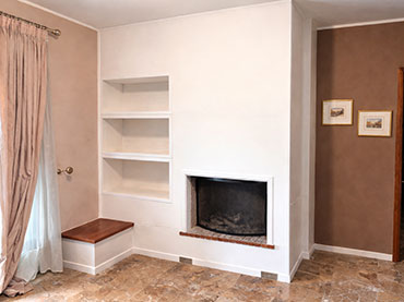 Τζάκι με λοξή καμινάδα, μετατροπή σε μοντέρνο με γυψοσανίδα και ράφια στο πλαϊ.